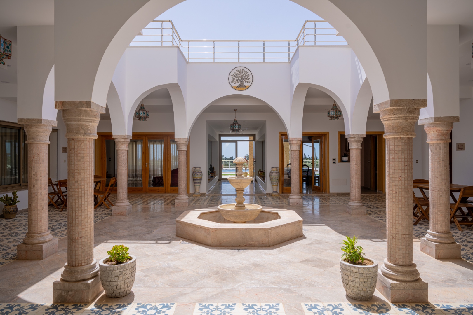 Patio intérieur d'une maison d'hôtes tunisienne avec colonnes, arcades et fontaine centrale